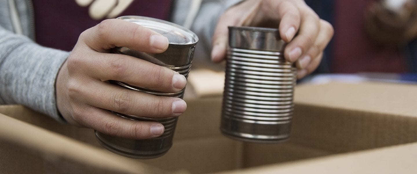 Volunteer packing tin cans into cardboard box