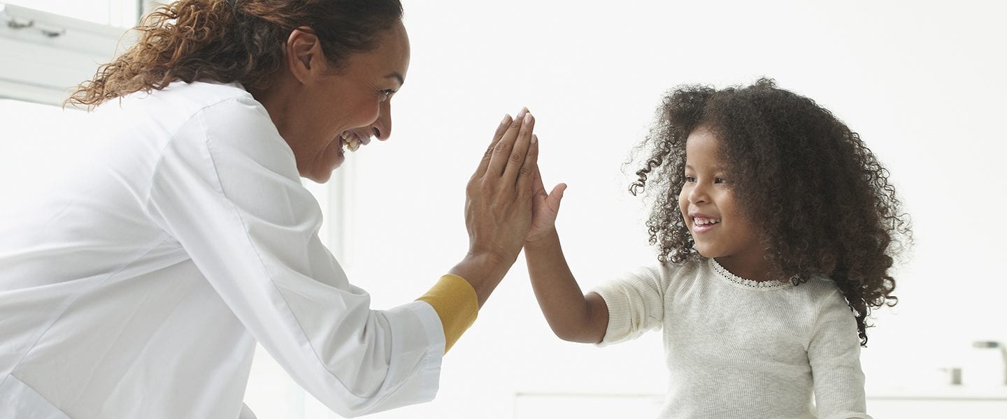Doctor and girl high-fiving in office
