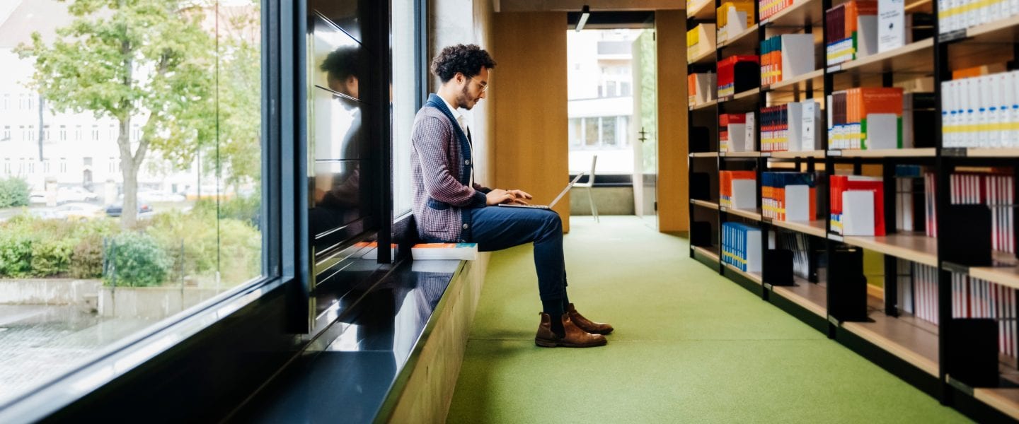 Man on laptop in a library