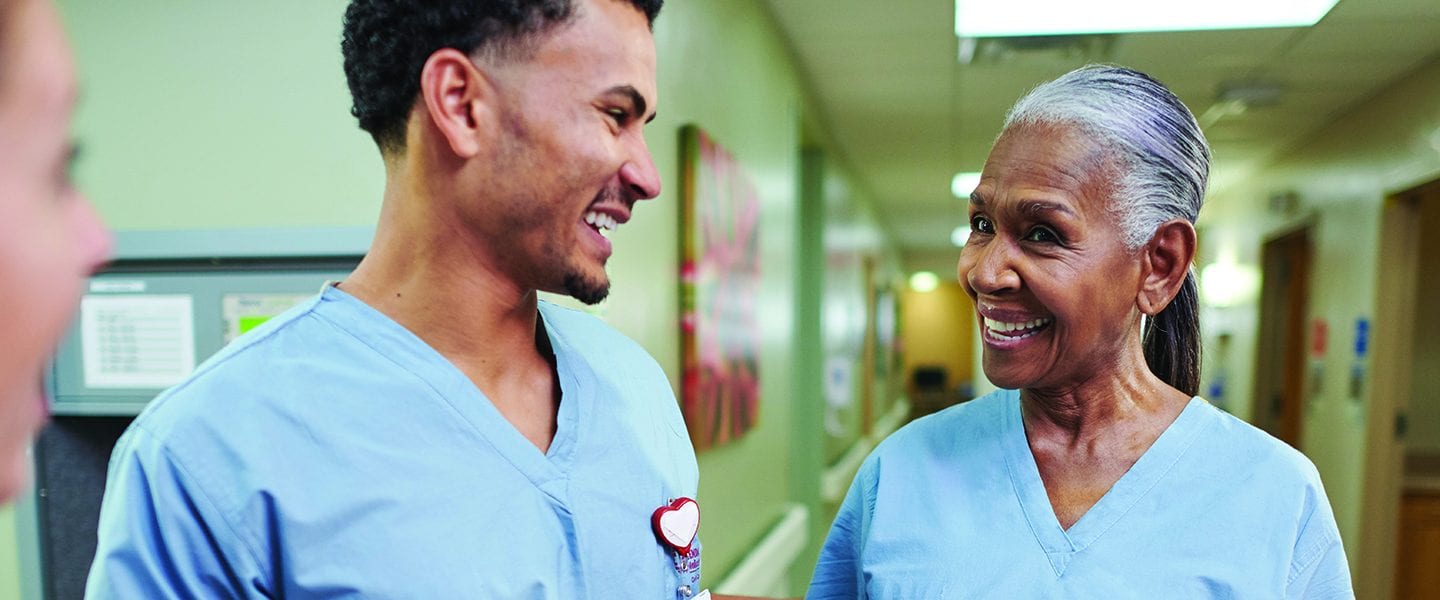 Health care professionals greet each other in a hallway