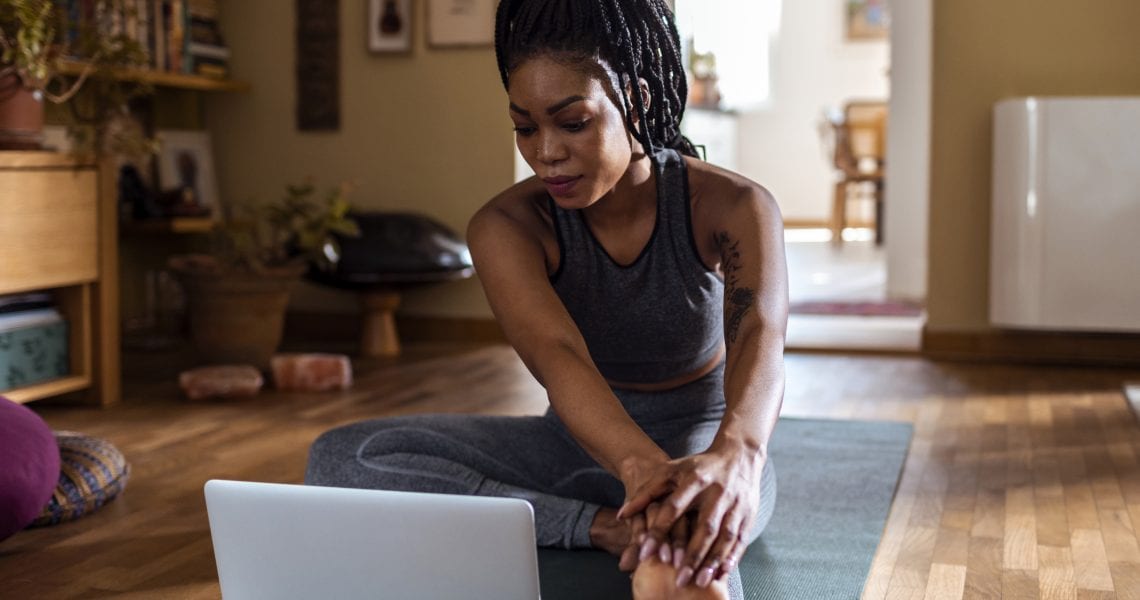 Close up of a young woman learning yoga online from her laptop