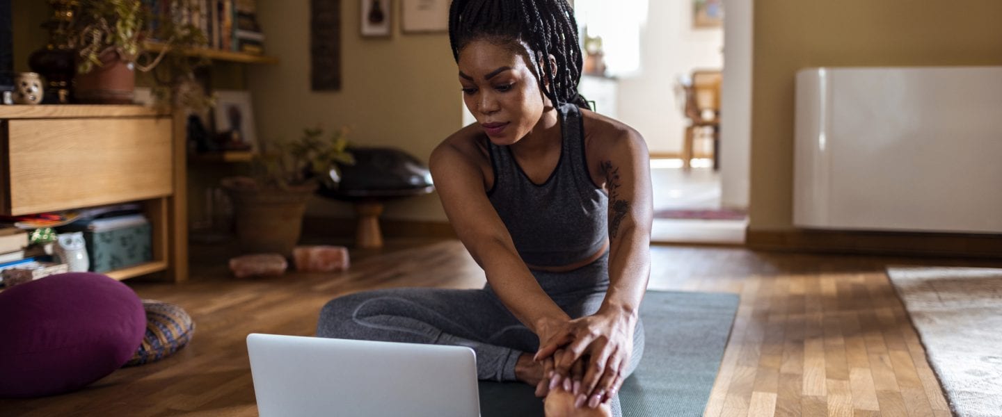 Close up of a young woman learning yoga online from her laptop